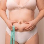 Closeup cropped of unrecognizable fat woman measuring her stomach